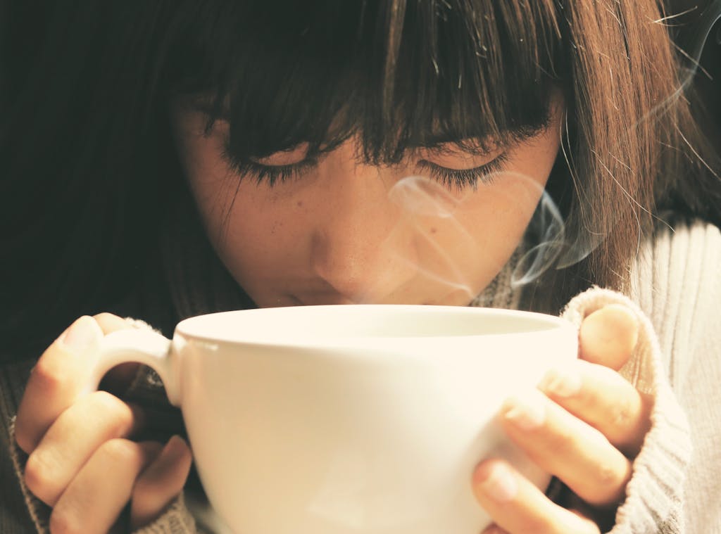 Woman savoring the aroma of a hot tea cup in a cozy setting